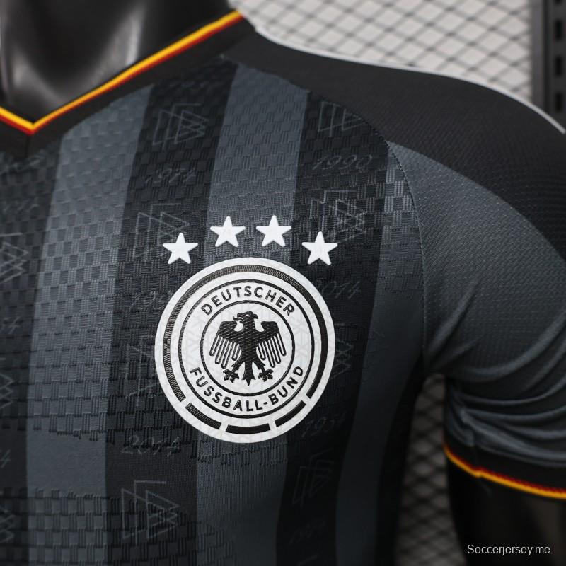 قميص اللاعب الإصدار 2026 ألمانيا باللون الرمادي الداكن مع شريط يرمز إلى سنوات الفوز بالبطولة
